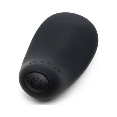 Pebble-shaped black silicone clitoral vibrator with a power button, designed for ergonomic handheld use.