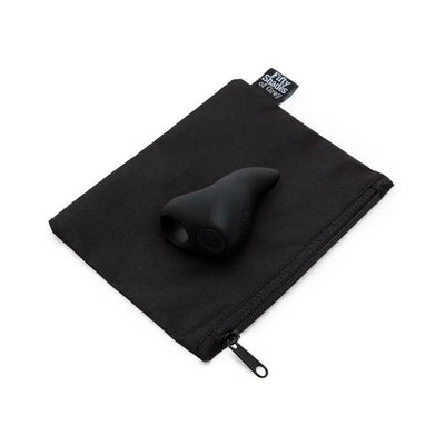 Black silicone finger vibrator with curved tip resting on a black zippered storage pouch labeled Fifty Shades of Grey.