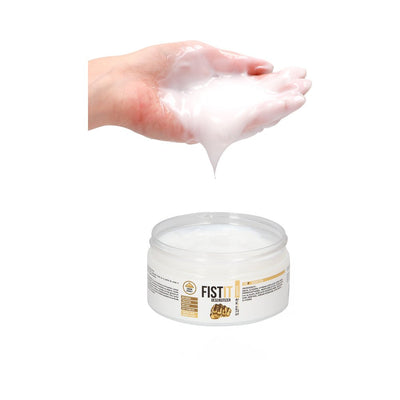 Hand holding thick white gel above open jar of Fist It Numbing lubricant cream.