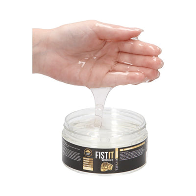 Hand holding clear gel lubricant dripping into an open jar of Fist It water-based lubricant.