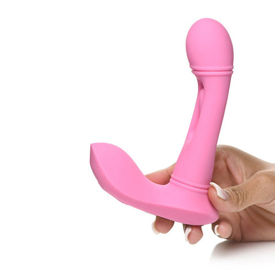 Hand holding a pink silicone G-spot vibrator with a curved flicking arm and ergonomic base.