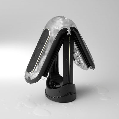 Black Flip Zero Vibration Stroker with transparent elastomer sleeve open on a charging base with water droplets.