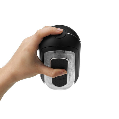 Hand holding the black Flip Zero Vibration Stroker showing the top button and transparent textured sleeve.