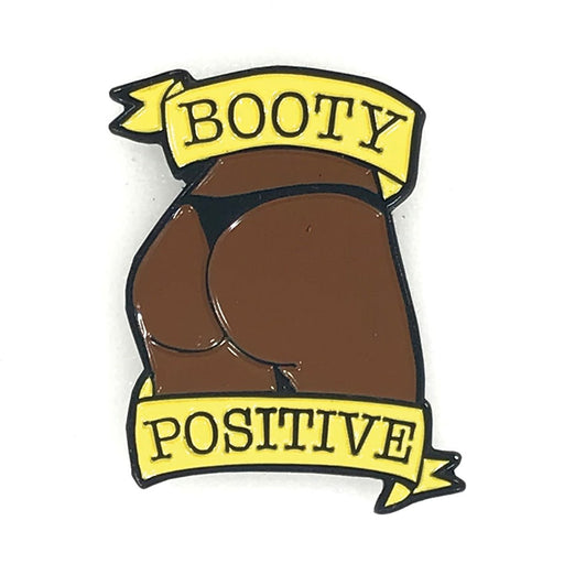 Chocolate brown enamel pin featuring a stylized booty with yellow banners reading Booty Positive.