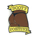 Chocolate brown enamel pin featuring a stylized booty with yellow banners reading Booty Positive.