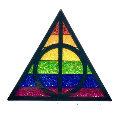 Triangle enamel pin with glitter rainbow stripes and black geometric design inspired by magical symbols.