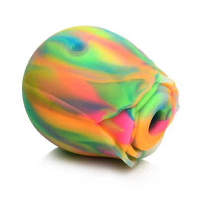 Rainbow-colored glow-in-the-dark rose-shaped clitoral stimulator with smooth silicone petals and central suction opening.