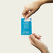 Hands holding and opening a single Good Clean Love Rebalance personal moisturizing and cleansing wipe packet.