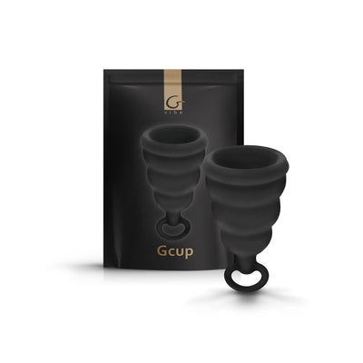 Black Gvibe Gcup menstrual cup with a soft silicone bell shape and pull tab, shown with sleek black packaging.