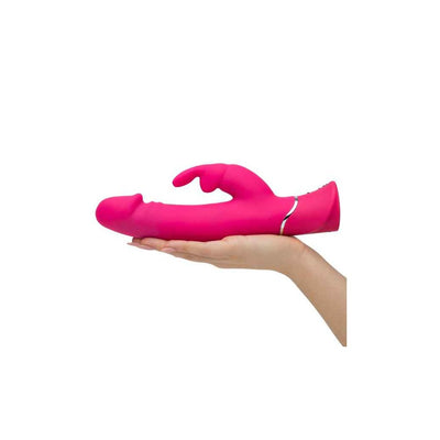 Hand holding a bright pink dual-density silicone rabbit vibrator with curved shaft and clitoral stimulator.