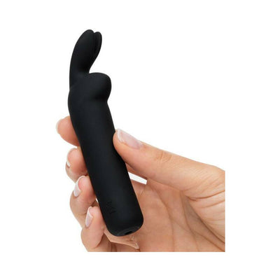 Hand holding a sleek black silicone Happy Rabbit rechargeable bullet vibrator with flexible bunny ears.