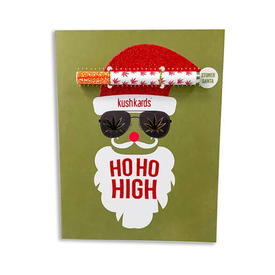 Holiday greeting card with a Santa face wearing sunglasses and a red glitter hat, featuring a one hitter pipe attached.
