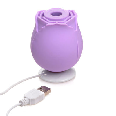 Purple rose-shaped silicone clitoral suction stimulator with USB charging cable on white background.