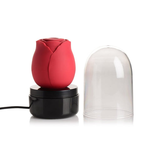 Red rose-shaped stimulator on black charging base with clear protective dome cover beside it on white background.