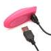 Pink silicone Inmi Spin N Grind charging with black USB cable on white background.