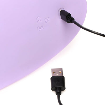 Close-up of a purple device being charged with a black USB cable plugged into its port.