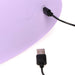 Close-up of a purple device being charged with a black USB cable plugged into its port.