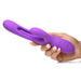 Hand holding a purple silicone Inmi Tri Flick rabbit vibrator with curved shaft, flicking arm, and control buttons.