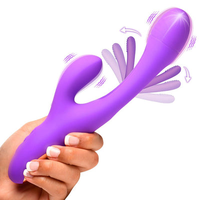 Hand holding a purple silicone rabbit vibrator with a curved shaft, flicking arm, and vibrating clitoral stimulator.