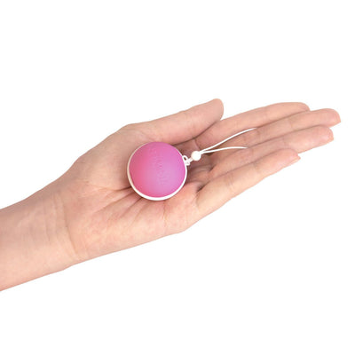 Hand holding a pink Intimina Laselle Medium 38g weighted pelvic floor exercise ball with a white retrieval cord.