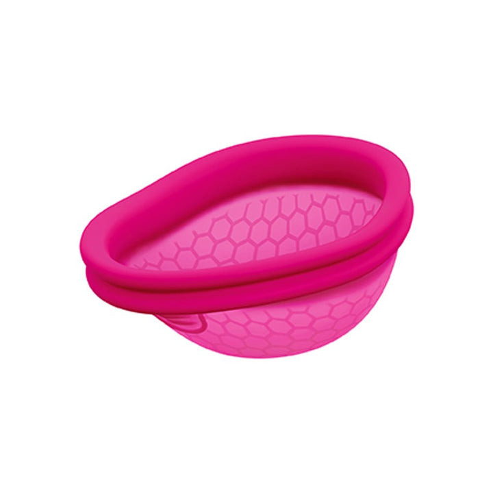 Pink reusable menstrual disc with a hexagonal pattern and a flexible rim for comfortable fit and leak protection.