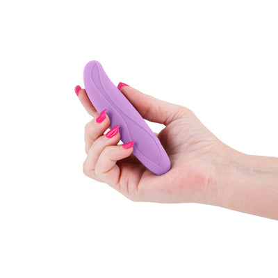 Hand holding a compact, bendable lilac silicone personal massager with a smooth, curved design.
