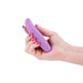 Hand holding a compact, bendable lilac silicone personal massager with a smooth, curved design.