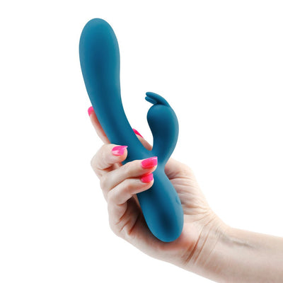 Hand holding a blue silicone INYA Luv Bunny vibrator with dual stimulation design and curved shape.