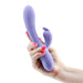 Hand holding a lavender silicone INYA Luv Bunny vibrator with a curved design and dual stimulation arms.