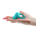 Hand holding a teal silicone vibrating ring designed for intimate use with a smooth ergonomic shape.