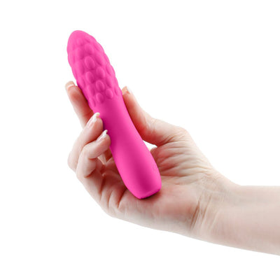 Hand holding a compact pink textured silicone vibrator with a rounded tip and raised bubble design.