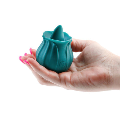 Hand holding dark teal rosebud-shaped silicone clitoral stimulator with a pointed tip and power button.