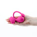 Hand holding a pink silicone wearable vibrator with a curved design and a small matching remote control.