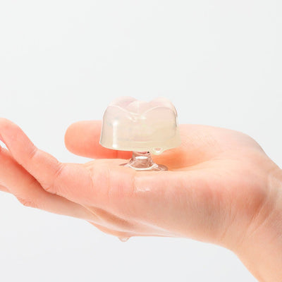 Hand holding a small, clear, flower-shaped iroha Petit LILY pleasure item with a smooth, translucent texture.