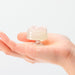 Hand holding a small, clear, flower-shaped iroha Petit LILY pleasure item with a smooth, translucent texture.