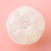 Top view of iroha Petit PLUM Clear compact disposable moisturizer on a pink background.