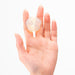 Hand holding a small, clear, flower-shaped single-use moisturizer capsule.