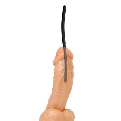 Black flexible silicone urethral sound inserted into a realistic flesh-toned model for demonstration.