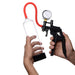 Hands holding a Jack Mate red penis pump with clear cylinder, pressure gauge, and ergonomic black hand pump.
