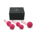 Set of three fuchsia silicone kegel balls with ergonomic loops displayed in front of a black Je Joue branded box.