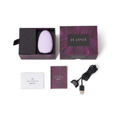 Je Joue Mimi Soft lilac clitoral vibrator with packaging, user manuals, and USB magnetic charging cable displayed on white background.