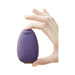 Hand holding the purple Je Joue Mimi Soft clitoral vibrator with a soft silicone tip against a white background.