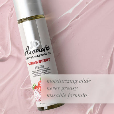 Bottle of JO Aromatix Strawberry scented massage oil on pink textured background with moisturizing glide text overlay.