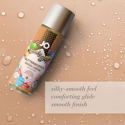 Bottle of JO Candy Shop Butterscotch flavored water-based personal lubricant on a beige background with water droplets and text describing its silky-smooth feel and comforting glide.