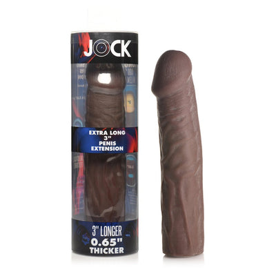 Jock extra long 3-inch penis extension sleeve in medium brown with lifelike texture next to its clear cylindrical packaging.