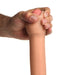 Hand squeezing the flexible, light-colored silicone dildo with realistic skin texture and pink tip against a white background.