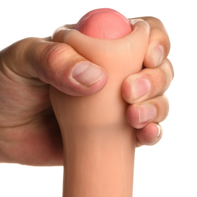Hand squeezing the tip of a light-toned silicone dildo with realistic texture and shape.