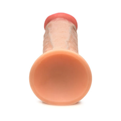 Light skin tone silicone dildo with suction cup base, realistic texture, and flexible design shown from base view.