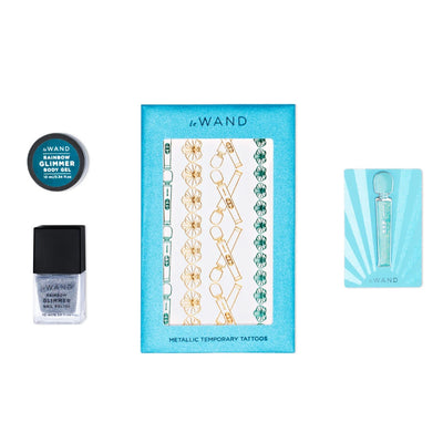 Le Wand All That Glimmers set featuring rainbow glimmer body gel, nail polish, metallic temporary tattoos, and enamel pin on blue background.