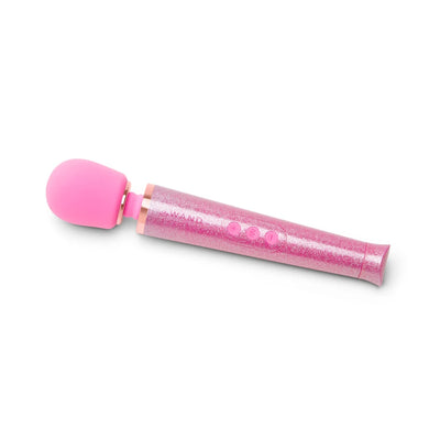 Pink glittery Le Wand Petite rechargeable massager wand with flexible head and three control buttons on white background.